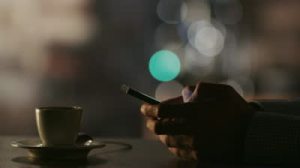 stock-footage-man-typing-a-message-using-mobile-phone-at-evening-time-in-coffee-house-close-up-shot-on-red